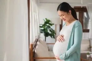 Asian young pregnant woman smile with big belly at home